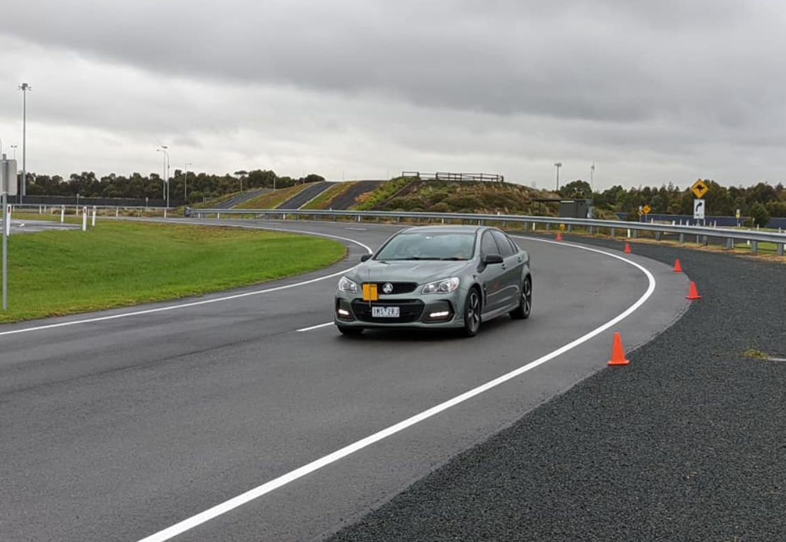 Driving school or test. Beautiful young woman with instructor learning how to drive and park car between cones.