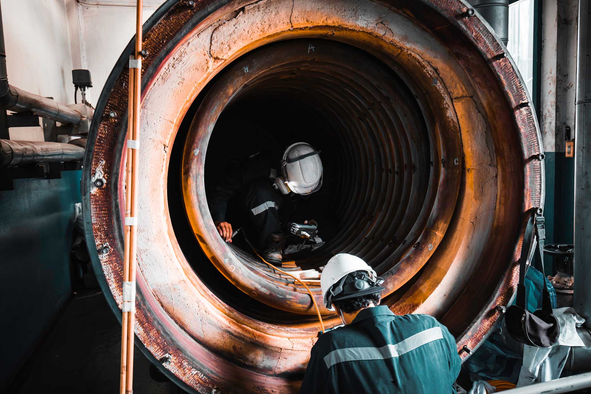 Male two worker inspection measured the coil pipe circular thickness of the boiler scan minimum thickness into danger confined space.
